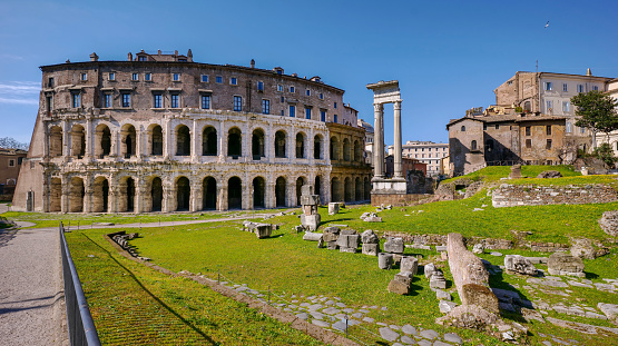 A suggestive view of the imposing archaeological area of the Theatre of Marcellus, located between the roman Jewish Ghetto (right) and the Capitoline hill or Campidoglio (Roman Capitol), in the historic core of Ancient Rome. Built in the southern area of the ancient Campus Martius, the Theatre of Marcellus it was completed in 13 BC and formally inaugurated in 12 BC from the Emperor Augustus, taking its name from his nephew Marcus Claudius Marcellus who died in 23 BC. The remaining columns (center) refer to the Temple of Apollo Sosianus, built starting from 413 BC and subsequently expanded during the Dynasty of the Augustus emperor. In 1980 the historic center of Rome was declared a World Heritage Site by Unesco. Super wide angle image in 16:9 and high definition format.