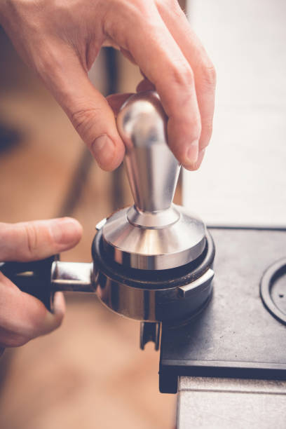 barista falsifiant le café dans portafilter en utilisant tamper. processus de préparation du café frais en gros plan - tampering photos et images de collection