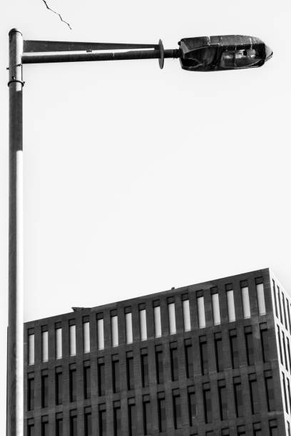 istock Vertical lamp post forming an inverted L pointing at a modern office building. Black and white. 1385922923