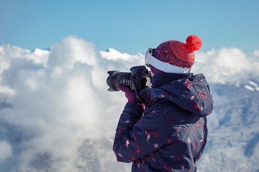 Female skier photographs in mountains, beautiful sunny day