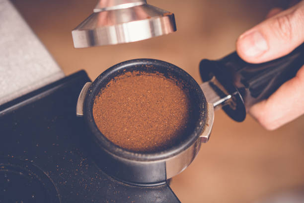 barista manomissione caffè in portafiltro usando tamper. processo di preparazione del caffè fresco ravvicinato - tampering foto e immagini stock