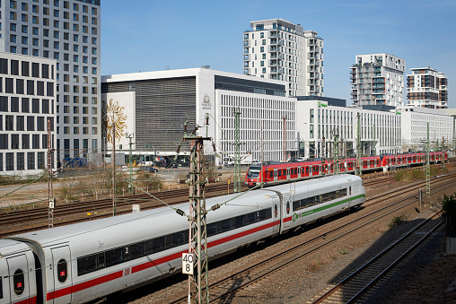 Düsseldorf, Germany - March 16, 2022: A german high speed train  ICE and a red commuter train in front of office buildings, hotels and apartment houses of the new urban quarter \