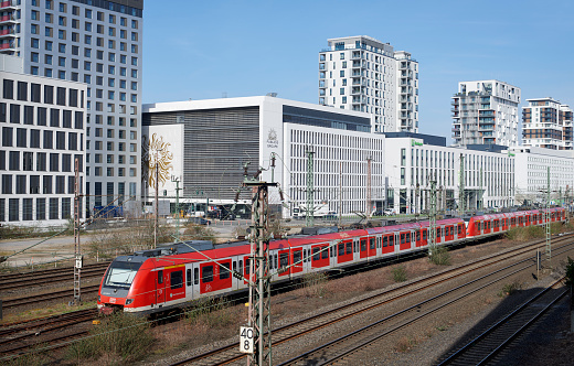 Düsseldorf, Germany - March 16, 2022: A german red commuter train (S-Bahn) in front of office buildings, hotels and apartment houses of the new urban quarter \