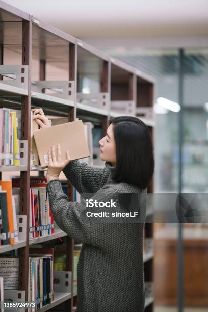 Asian Female Students Choose Books From Bookshelves In The Library Stock Photo - Download Image Now