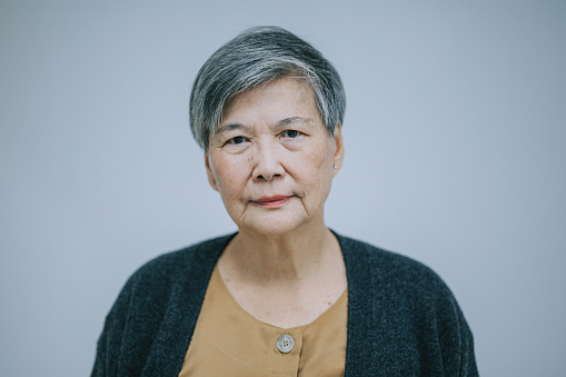 Portrait Asian Chinese senior woman looking at camera serious face with white background