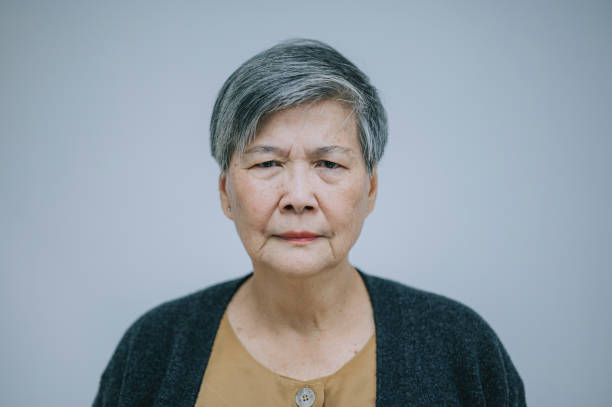 портрет азиатской китаянки пожилой женщины смотрит на камеру серьезного лица с белым фоном - distraught 70s asian ethnicity women стоковые фото и изображения