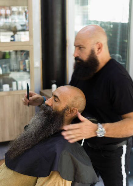 istock bearded man sitting on a client seat being served by a barber 1385930529