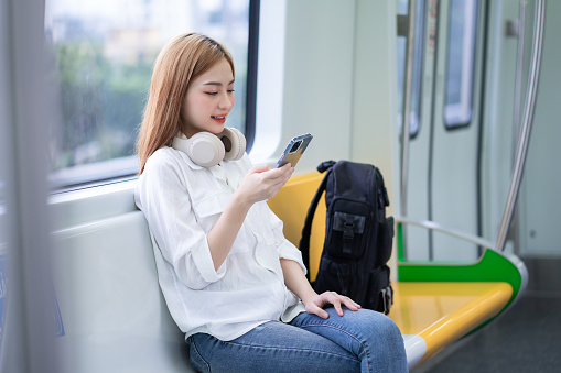 Image of young Asian woman using smartphone on the metro