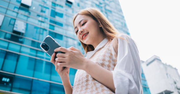 istock Young Asian woman using smartphone on street 1385931525