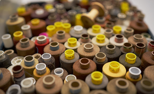 Rows of spools of thread of different colors in a box in the studio.