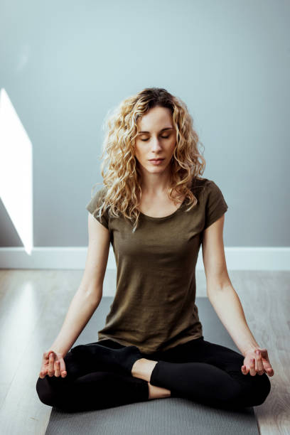 jovem mulher fazendo yoga em casa - lotus position - fotografias e filmes do acervo