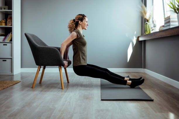 istock Woman performing exercise inside her home with a chair. 1385933319