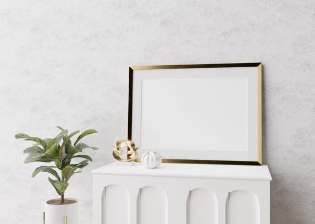 istock Empty picture frame standing on white console in modern living room. Mock up interior in minimalist, scandinavian style. Free space for picture. Console, plant, vase. 3D rendering. 1385933501