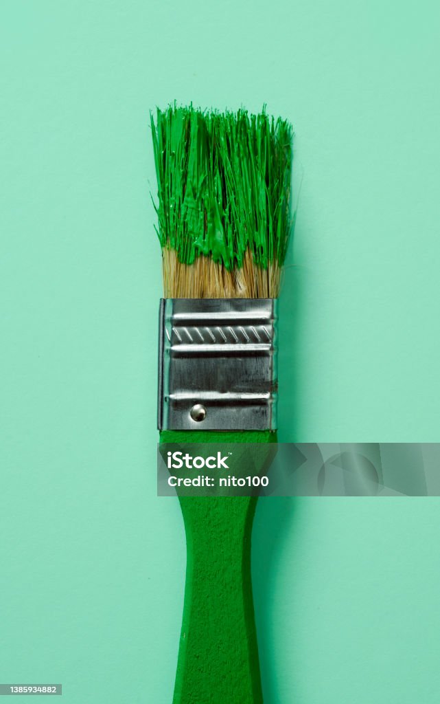 paintbrush with green paint closeup of a green paintbrush with green pain, on a pale green background Greenwashing Stock Photo