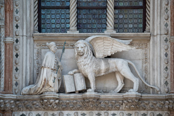 istock Winged Lion and a priest with a Bible at St. Mark's Square 1385935722