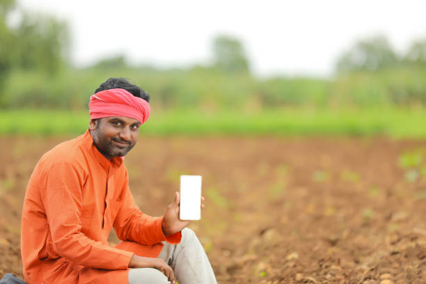technology concept : Young indian farmer showing smartphone. stock photo