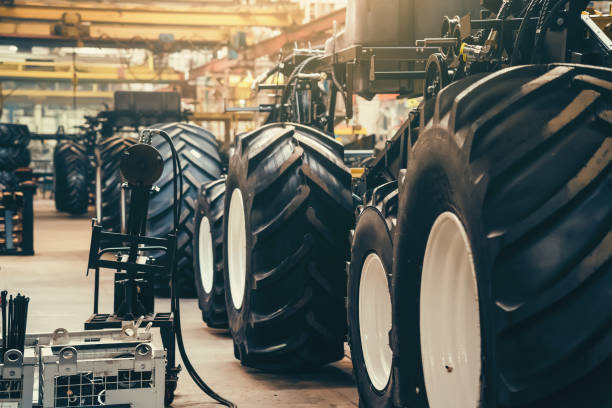 linha transportadora para produção e montagem de grandes máquinas industriais, tratores ou combinações. grandes pneus de borracha na fábrica - heavy plant - fotografias e filmes do acervo