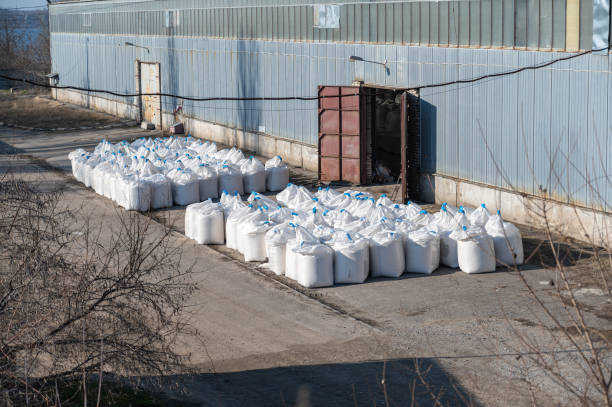 istock Stack of large bags next to a concealed industrial warehouse outdoors. Cargo handling and storage. 1385941675