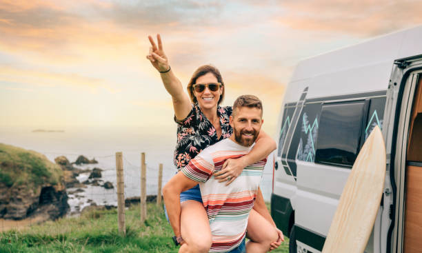 istock Couple looking camera having fun piggybacking next to their camper van 1385942901
