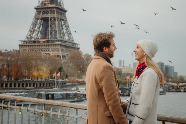istock Romantic couple flirts while standing on a bridge at Seine River in front of Eiffel tower, Paris 1385942990