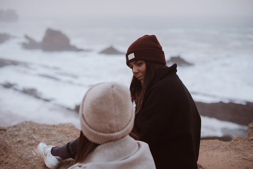 Two women hanging out by the sea in winter