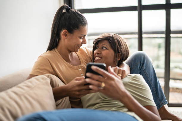 istock Lesbian couple using the mobile phone at home 1385944937