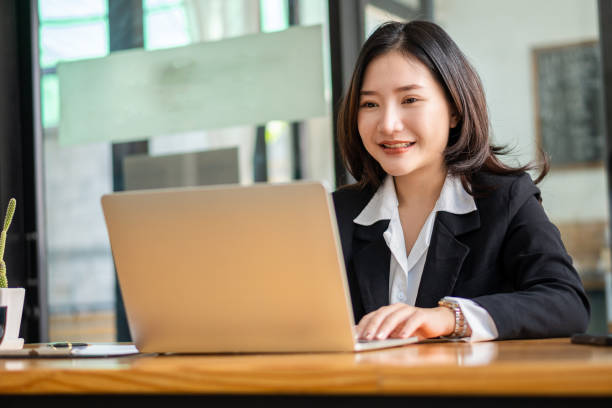 istock working concept Asian businesswoman using laptop Internet communication with customers at coffee shops Attractive woman sitting on laptop and smartphone in beverage restaurant 1385945047