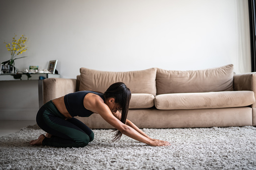 Mid adult woman stretching at home