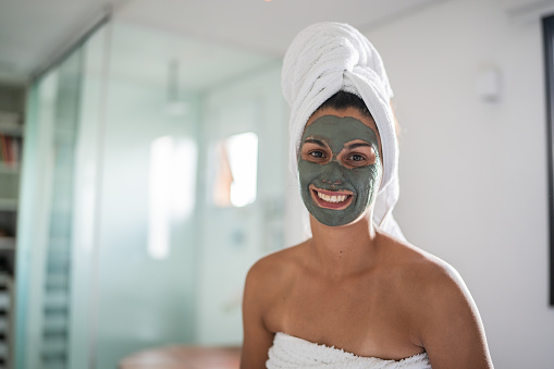 Portrait of a mid adult woman with facial mask in the bathroom