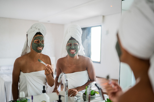 Female couple applying facial mask in the bathroom