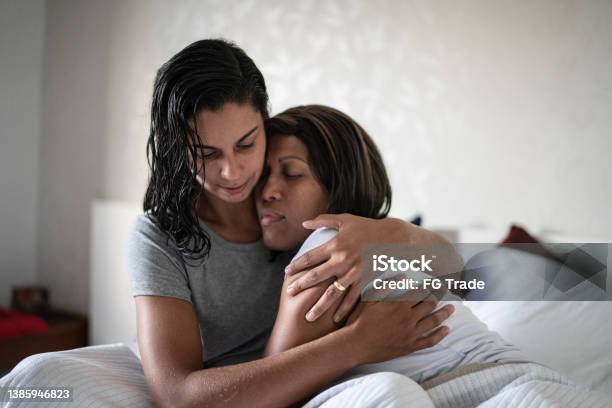 Lesbian couple hugging in the bed at home