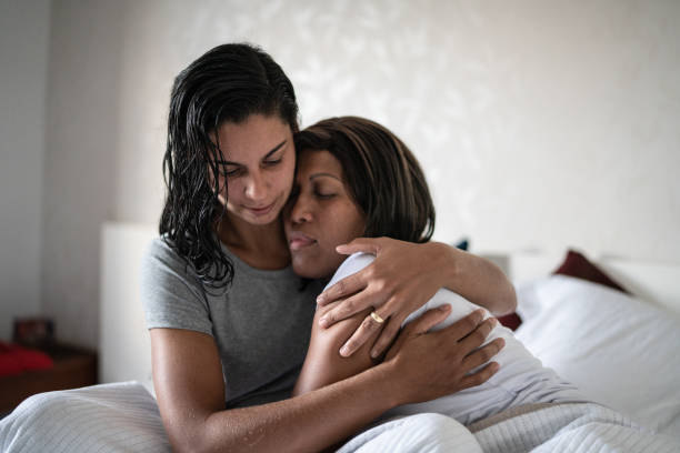 Lesbian couple hugging in the bed at home Lesbian couple hugging in the bed at home sad gay stock pictures, royalty-free photos & images