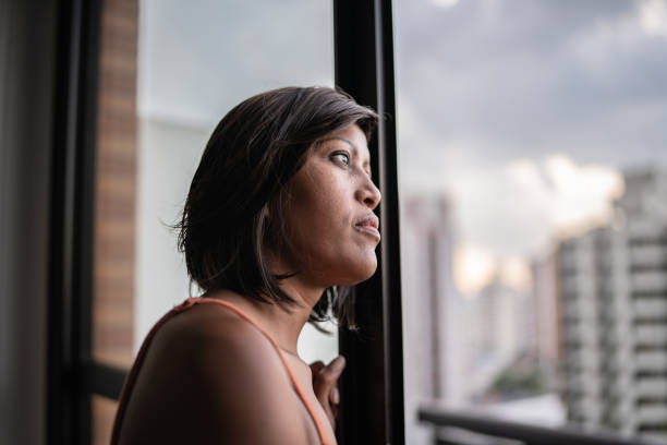 istock Contemplative woman looking through the window at home 1385946880