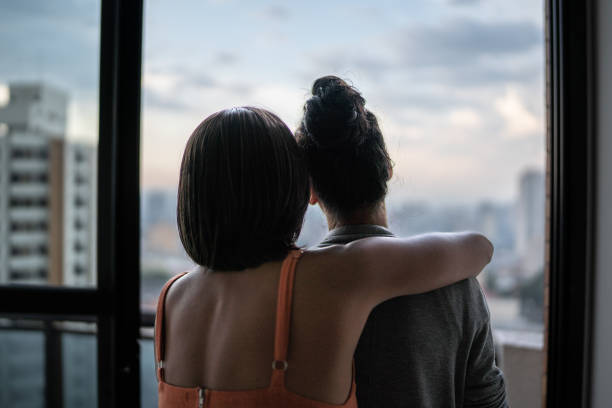 istock Lesbian couple looking through window at home 1385946895