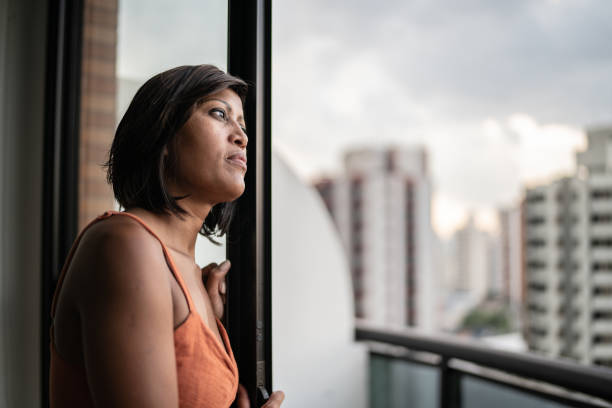 istock Contemplative woman looking through the window at home 1385946896