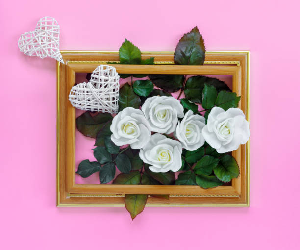 hermosas rosas blancas con follaje verde y corazones en marco de madera vintage en la pared rosa brillante para el día de san valentín. tarjeta de felicitación creativa. - invitation birthday card creativity ideas fotografías e imágenes de stock