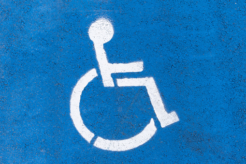 Symbol of a disabled parking space painted on asphalt.