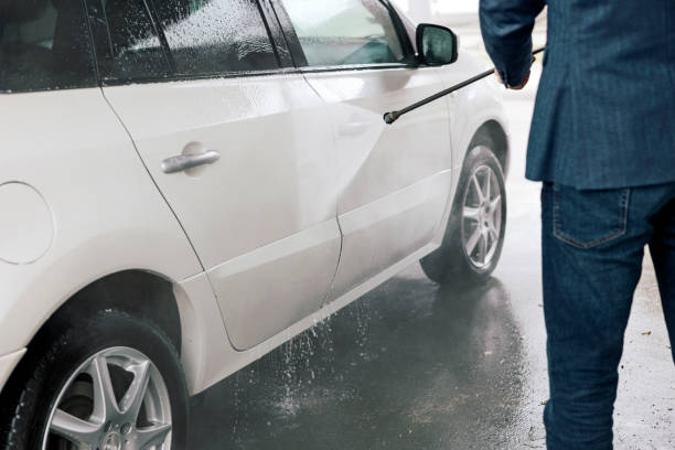 istock Young man washes the car with a hose 1385951119