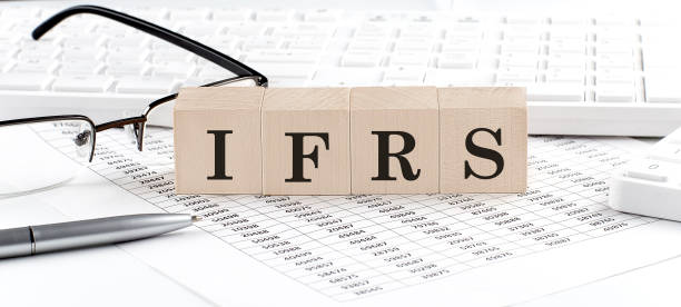 IFRS written on wooden cube with keyboard , calculator, chart,glasses.Business concept stock photo