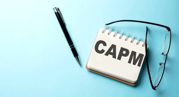 Photo of CAPM text written on a notepad on the blue background