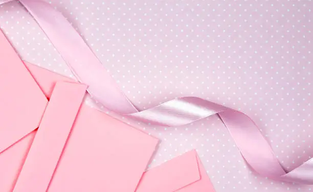 Pink envelopes and pinkribbon on the pink background.Copy space