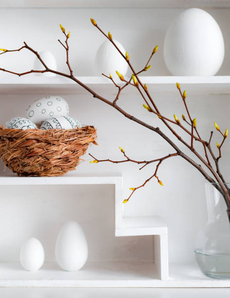 istock Home minimalist interior with Easter decor. Branches with budding buds in a glass vase on shelves in the shape of a house, 1385952100