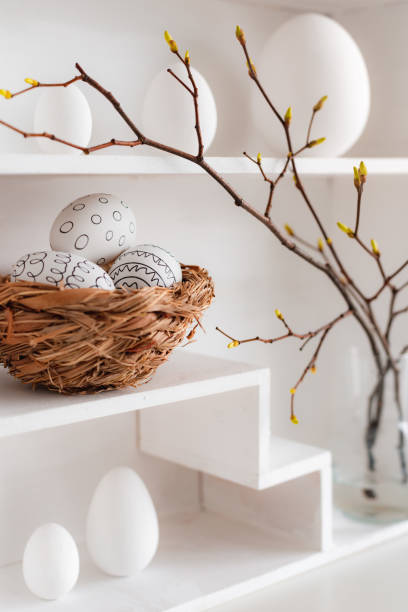istock Home minimalist interior with Easter decor. Branches with budding buds in a glass vase on shelves in the shape of a house, 1385952110
