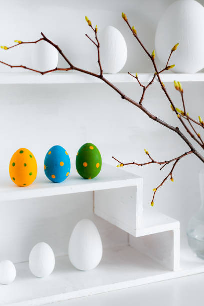 istock Home minimalist interior with Easter decor. Branches with budding buds in a glass vase on shelves in the shape of a house, 1385952120