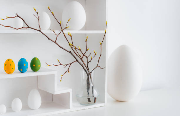 istock Home minimalist interior with Easter decor. Branches with budding buds in a glass vase on shelves in the shape of a house, 1385952129
