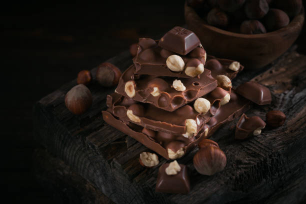 istock Pile of hazelnut milk chocolate and nuts on dark background 1385955248