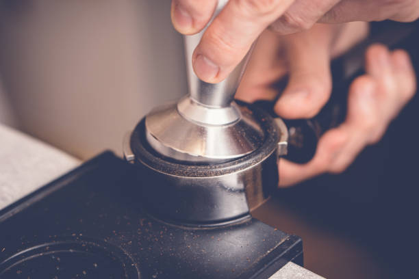 barista manomissione caffè in portafiltro usando tamper. processo di preparazione del caffè fresco ravvicinato - tampering foto e immagini stock