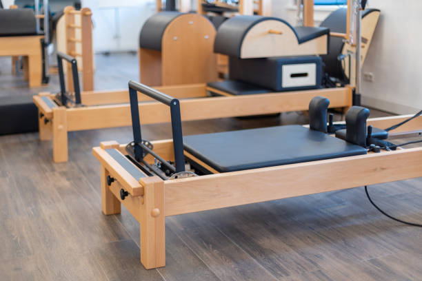 mesas de estiramiento de pilates fitness y otros equipos de ejercicio en el gimnasio - pilates health club gym exercising fotografías e imágenes de stock