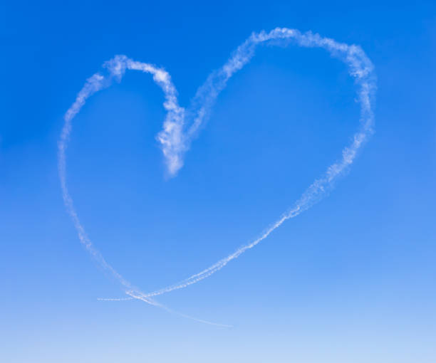 istock Heart shape formed by white smoke in the clear blue sky. 1385971819