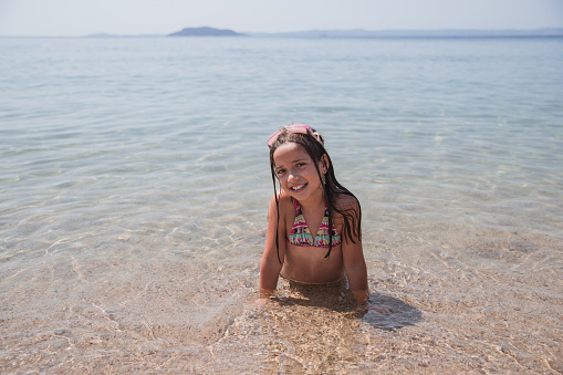 Teenage girl with swimming goggles on her head having a great time in a sea water, resting and sunbathing